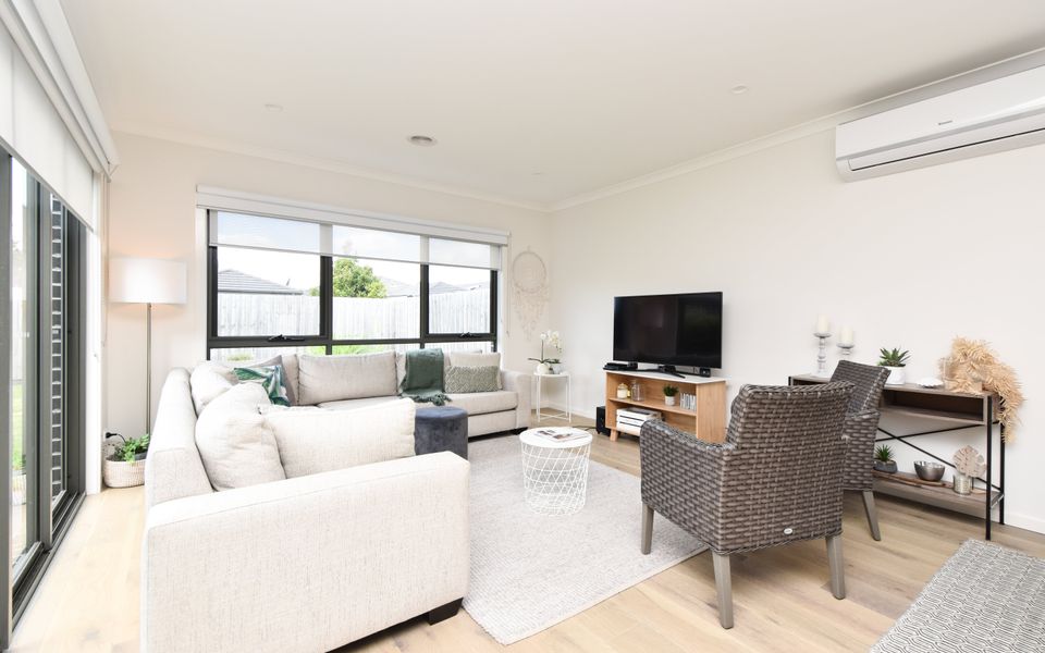 Comfortable L-shaped lounge and armchairs with TV and sliding door access to the yard.