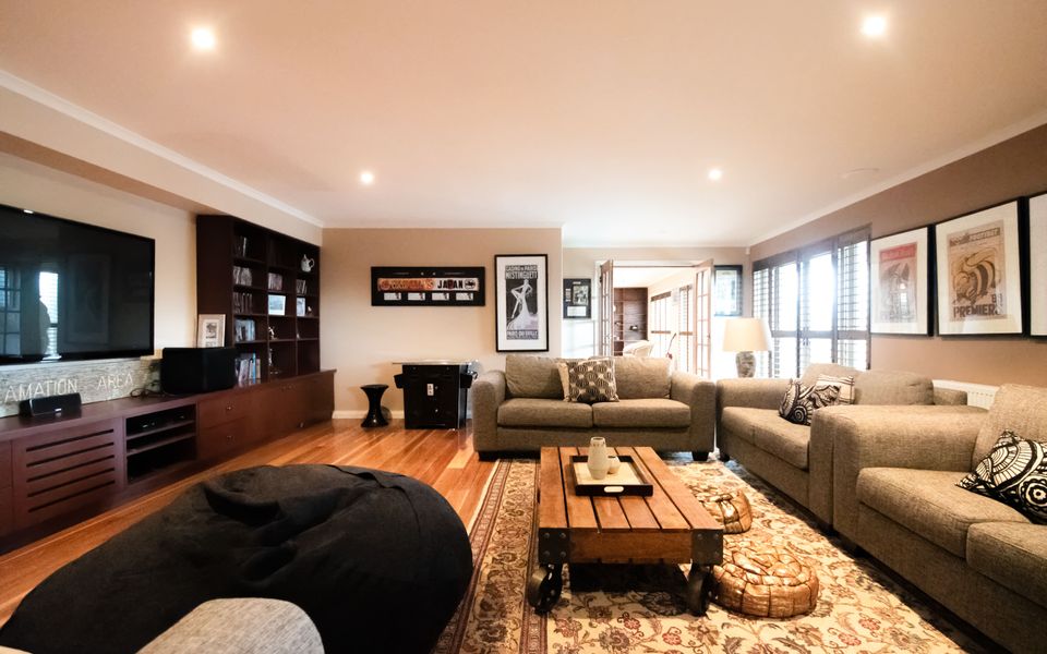 Large cozy cinema room with low lighting, 3 comfy sofas, large TV and kitchenette.