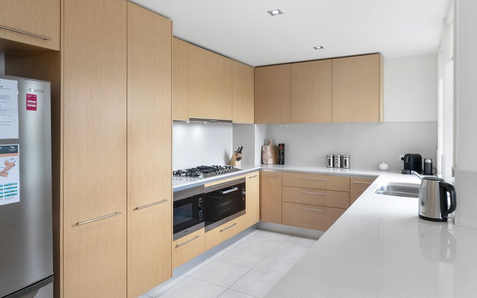 Kitchen equipped with microwave, oven, cooktop, coffee machine, rice maker and fridge freezer.